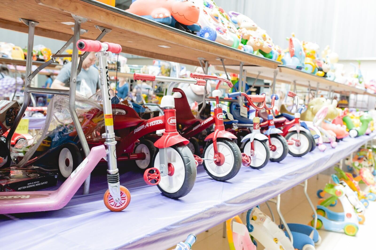 A smiling Team Member stands behind a rack of toddler girl's clothing at the sale.